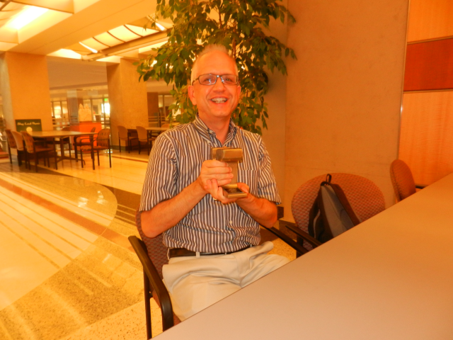 David Bickford posing with his piece of the light rail track he redeemed from the Rewards Store.