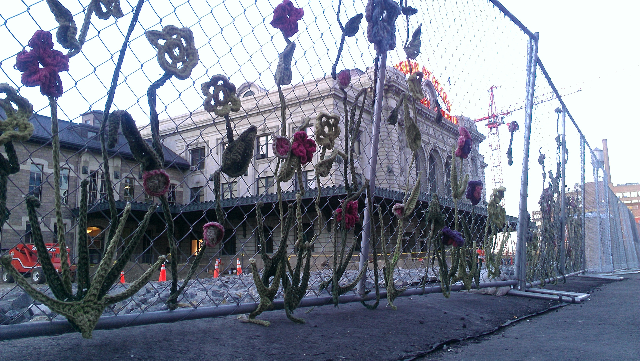 Local artisans have personalized a construction site with knitted flowers.